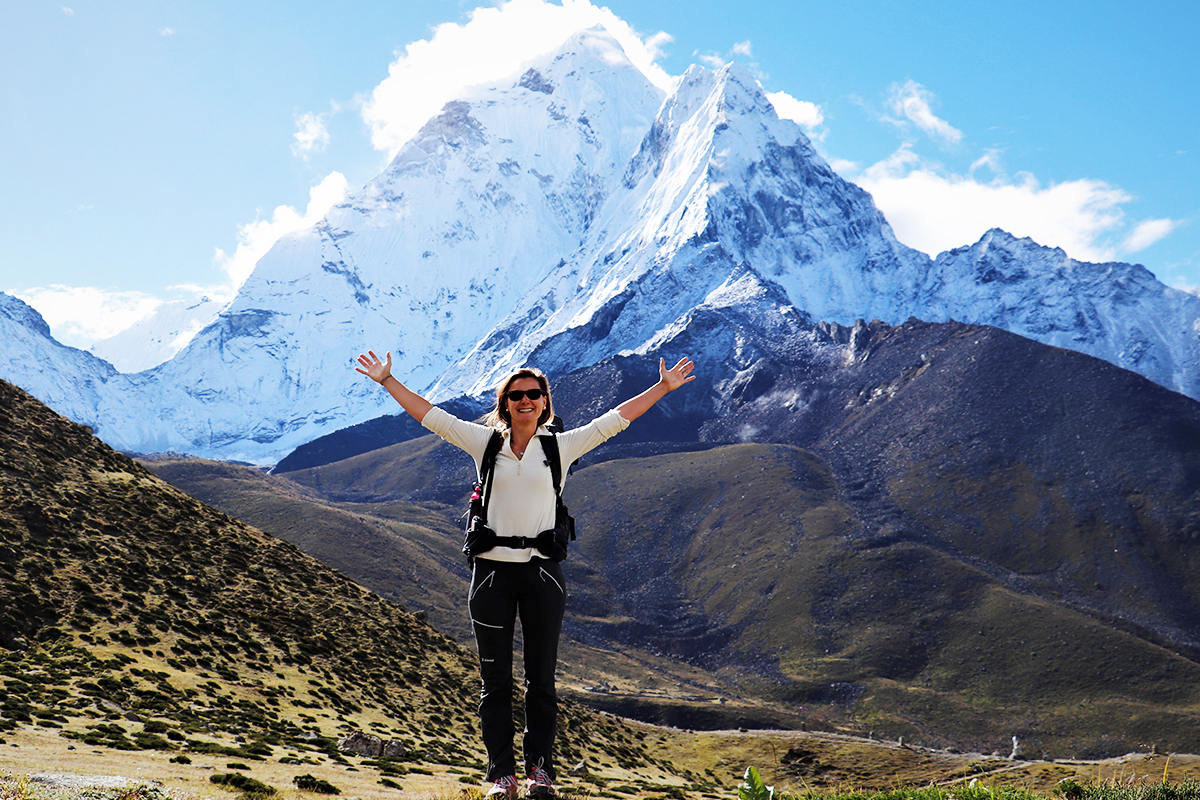 Ama Dablam on background of a female trekker trekking down the mountain